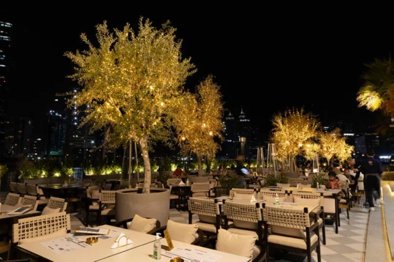 The terrace after dark, lit gold against the city