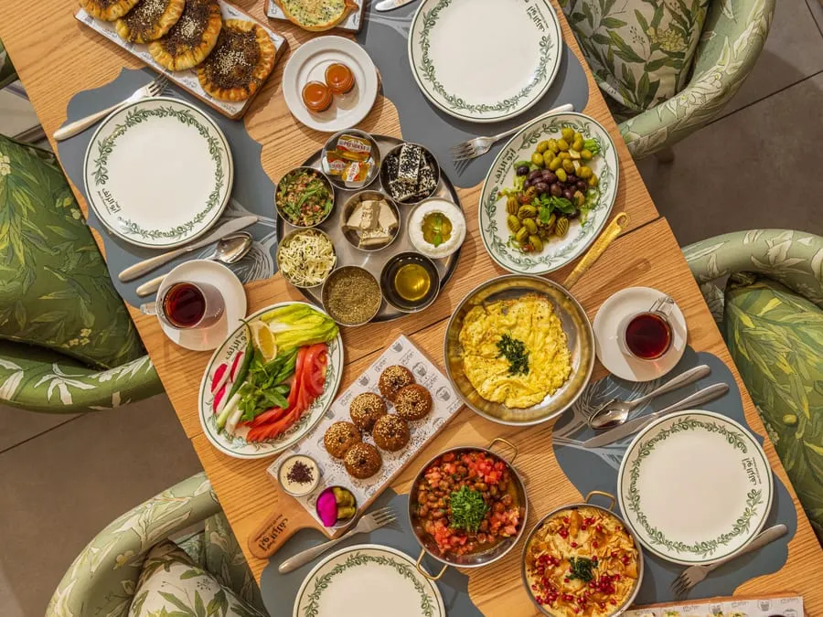 A breakfast spread seen from above: falafel, mezze, eggs and tea