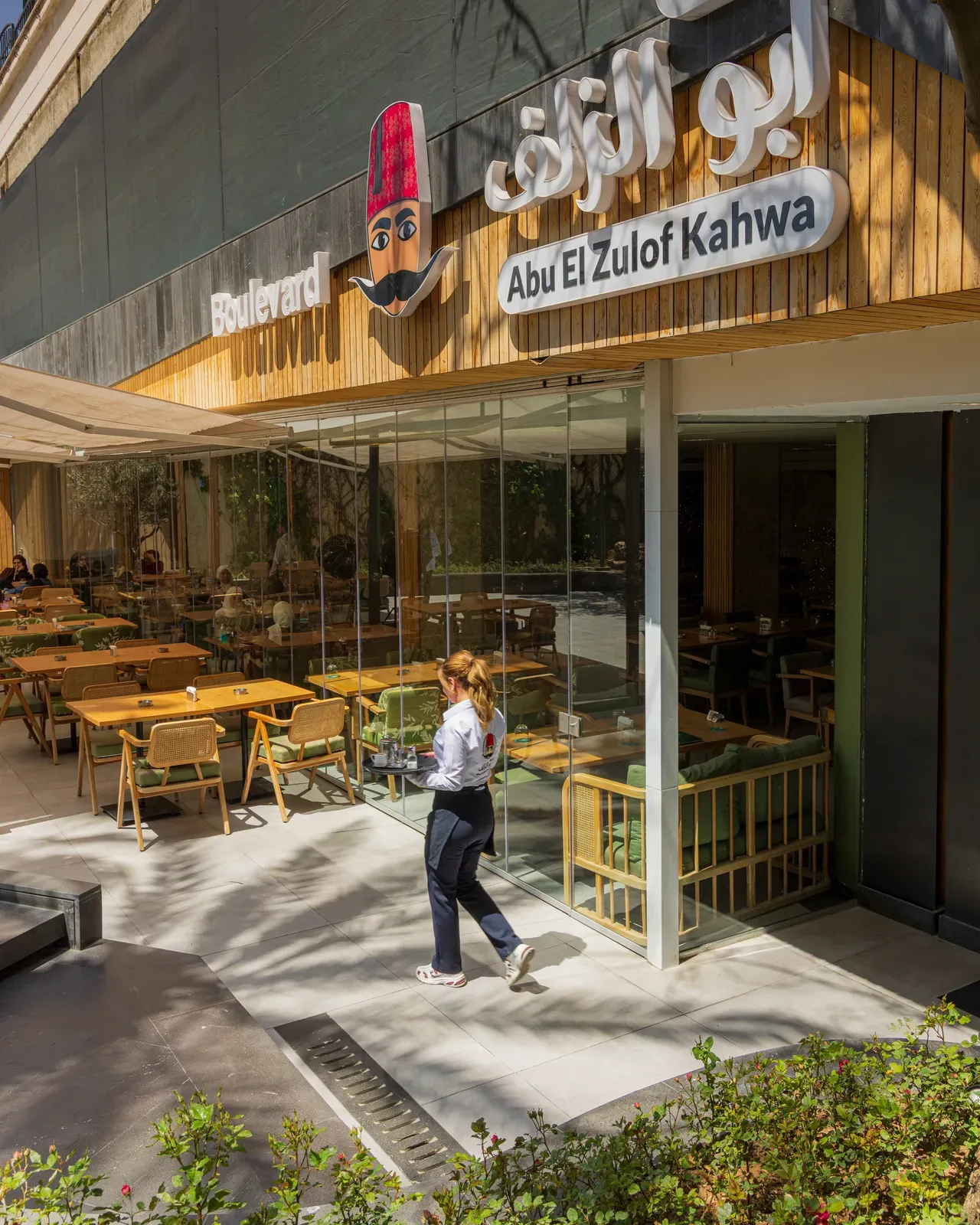 A waitress crossing the terrace in front of the café on a sunny day
