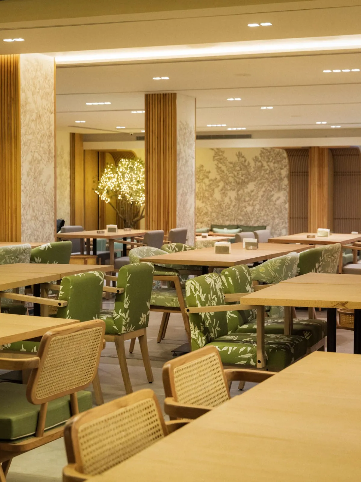 The dining room: olive-print chairs, botanical walls and a tree of lights