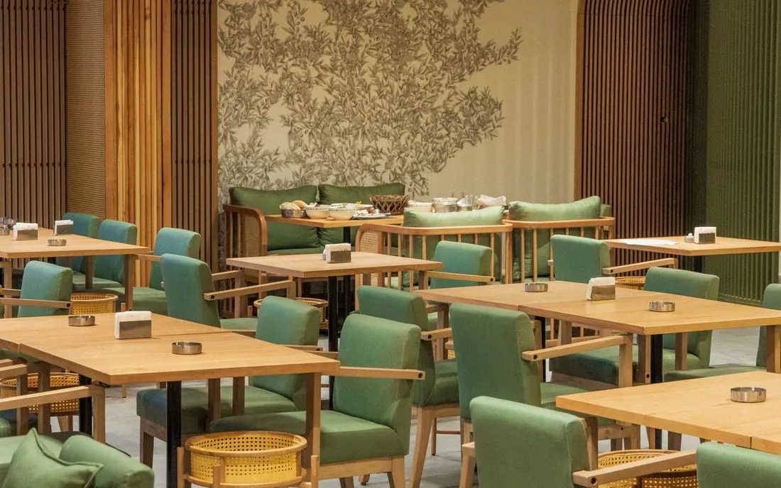 The dining room, olive-green chairs beneath a wall of drawn olive branches