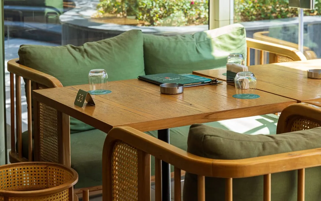Green sofas and cane chairs around tables by the window