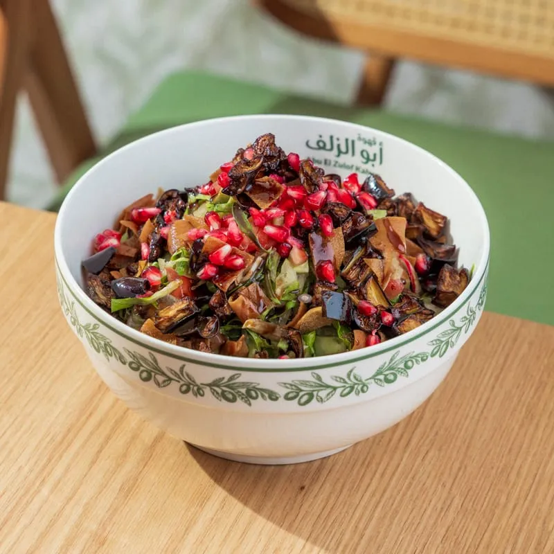 A bowl of roasted aubergine salad with pomegranate seeds