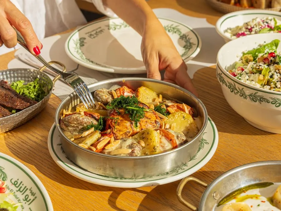 Hands serving from shared pans of hot dishes