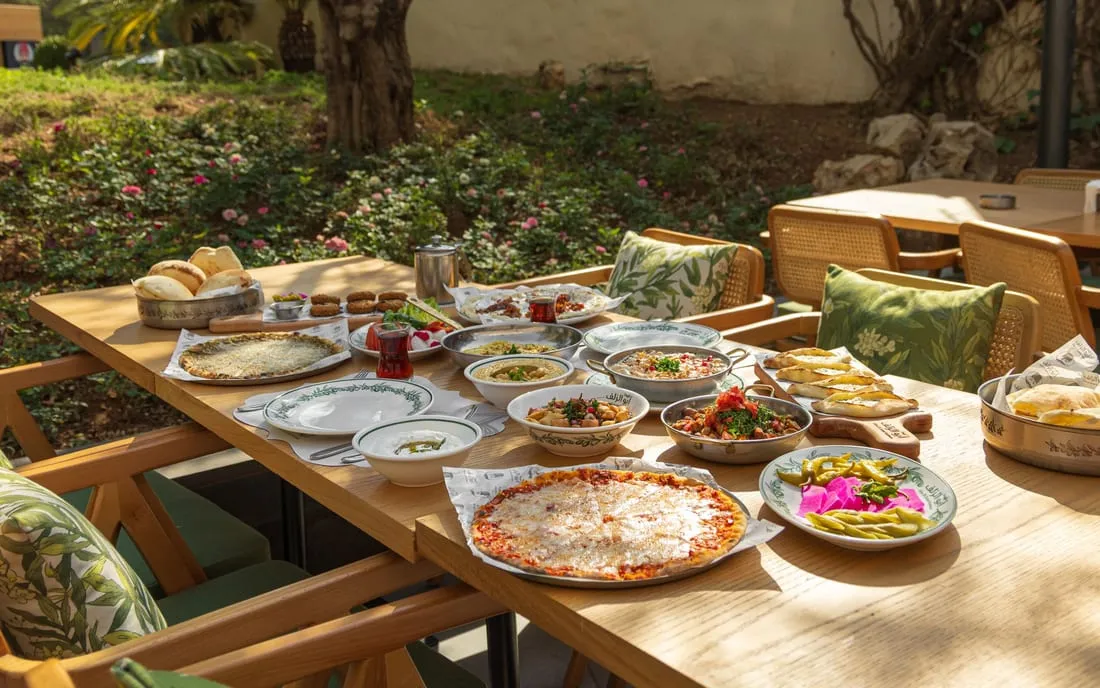 A long table of mezze set out in the garden beneath olive trees